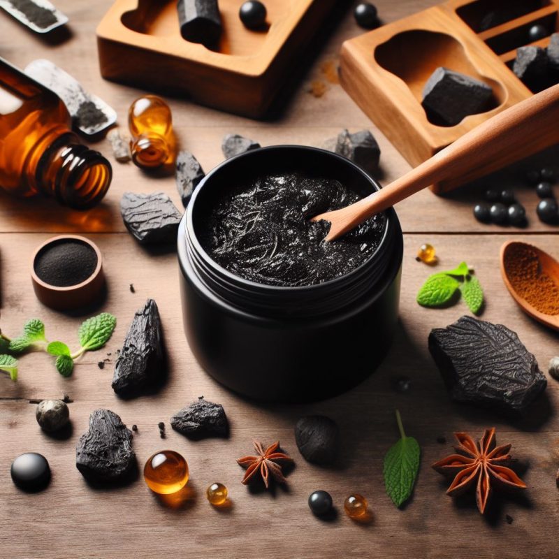 Opened jar of black Shilajit resin on a wooden surface with a wooden spoon, surrounded by natural health ingredients like star anise, green leaves, supplements in amber bottles, and raw Shilajit pieces, showcasing a setting of holistic wellness products.
